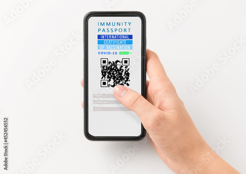coronavirus, technology and health concept - close up of woman's hand holding and showing smartphone with international certificate of covid-19 vaccination on screen over white background