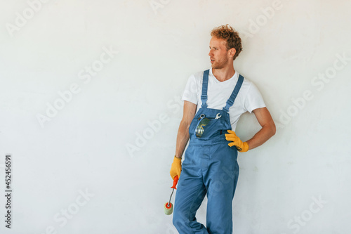 Against white walls. Young man working in uniform at construction at daytime