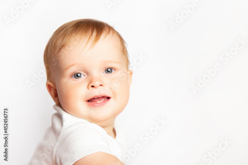 portrait of cute smiling blond caucasian baby boy in a white T-shirt on white background with copy space