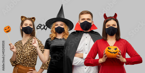 holiday, health and pandemic concept - friends in halloween costumes and black r Fotobehang