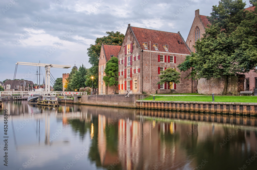 Zwolle, The Netherlands, August 4, 2021: historic buildings, trees and a drawbridge reflect in the smooth water of Thorbecke canal on a summer evening