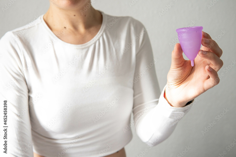 Young woman hand holding menstrual cup with white background