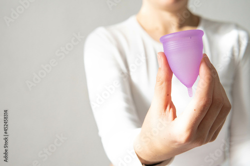 Young woman hand holding menstrual cup with white background 
