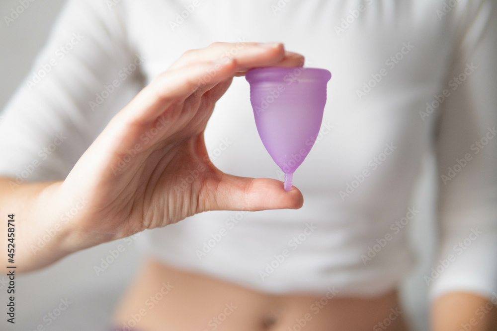 Young woman hand holding menstrual cup with white background