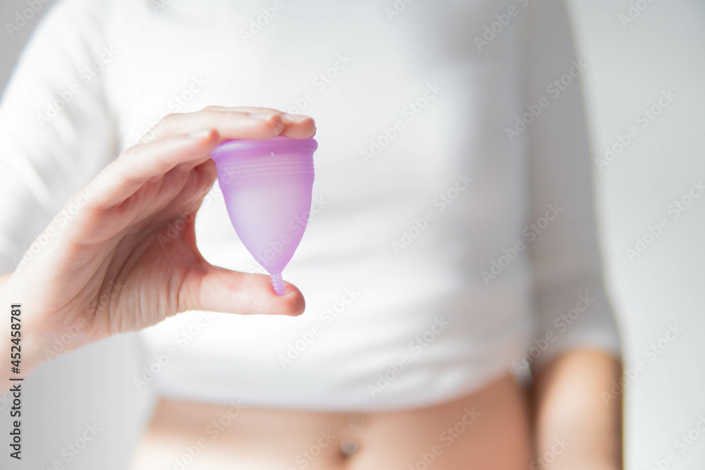 Young woman hand holding menstrual cup with white background