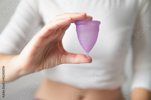 Young woman hand holding menstrual cup with white background 