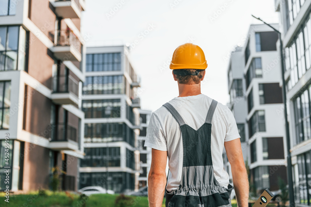 Rear view. Young man working in uniform at construction at daytime Rear view. Young man working in uniform at construction at daytime