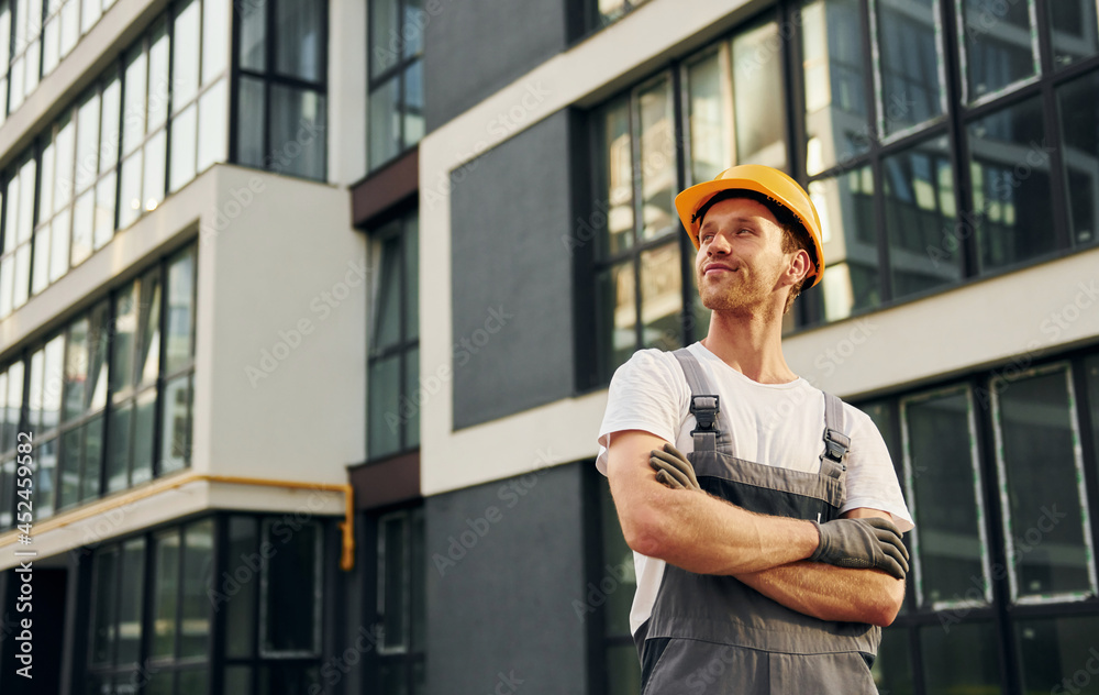 Modern exterior. Young man working in uniform at construction at daytime Modern exterior. Young man working in uniform at construction at daytime