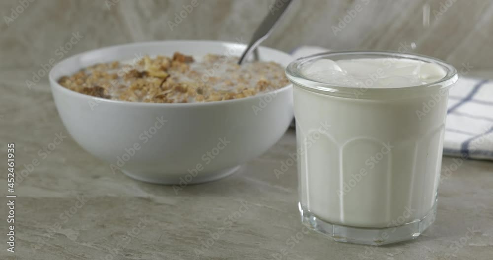 Pouring milk into a glass by a bowl of granola breakfast cereal
Pouring milk into a glass by a bowl of granola breakfast cereal