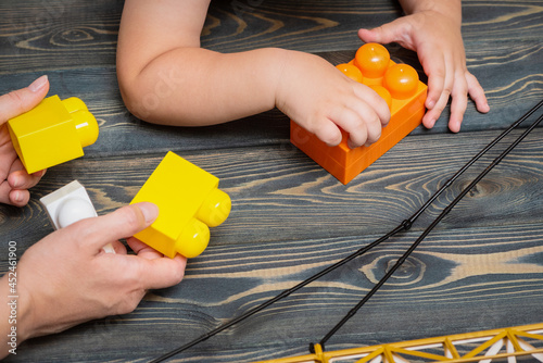 Woman is playing with a child in the toy building kit close up.