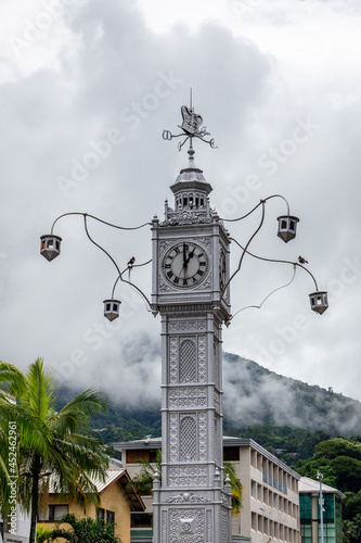 The Victoria Clock Tower  or  mini Big Ben   copy of London s Big Ben in the city center of Victoria  Seychelles  capital  with cloudy sky and palm trees in the background.