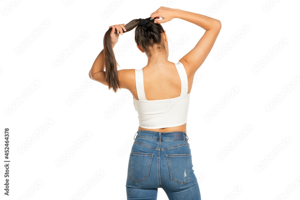 Back view of a young woman adjusting her hair in a ponytail Back view of a young woman adjusting her hair in a ponytail