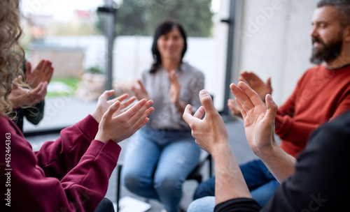 Men and women sitting in circle during group therapy, clapping.