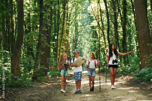 With map. Kids strolling in the forest with travel equipment