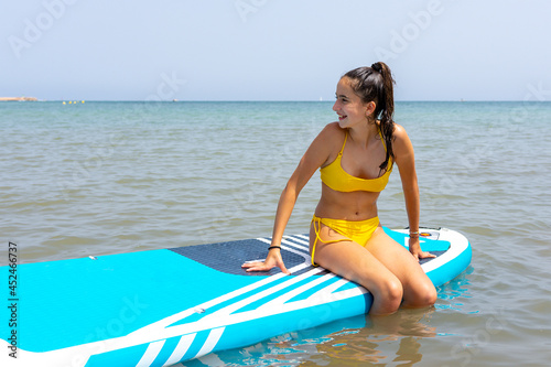 Photography Teenage sitting on a paddle surf board floating on the sea