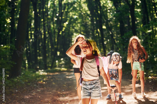 Girl looking far away. Kids strolling in the forest with travel equipment