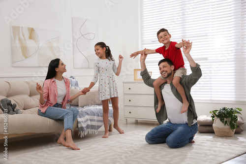 Happy family with children having fun in living room. Adoption concept