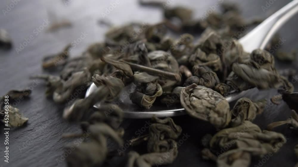 Dry green tea leaves fall into a metal teaspoon on a black kitchen slate stone. Macro. Slow motion. Dolly Shot Dry green tea leaves fall into a metal teaspoon on a black kitchen slate stone. Macro. Slow motion. Dolly Shot