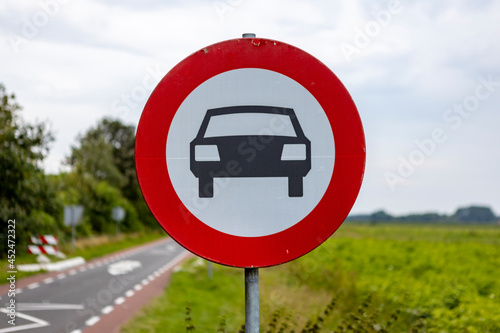 Dutch sign with red band showing an icon of a car meaning no entry for personal vehicles approaching a traffic bump too high to go over