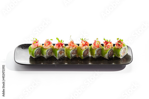 Shrimp Sushi Roll on black slate plate. Luxury maki sushi roll with cream cheese and shrimp inside. Seafood sushi roll topped with spicy scallop. Isolated on white background. photo