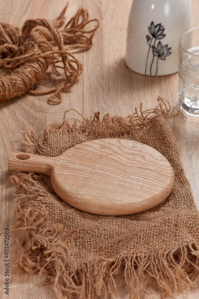 Mockup for product, food and beverage. Wooden plate in burlap, glass of water on wooden table. Clean. Nobody