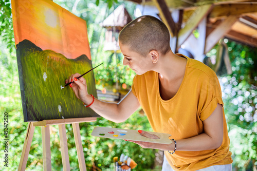 Foto Young female artist working on her art canvas painting outdoors in her garden