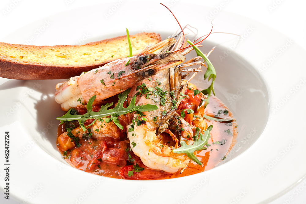 Seafood with tomato sauce on white restaurant plate. Shrimp seafood and tomato stew garnished with fried bread. Isolated on white background. Seafood with tomato sauce on white restaurant plate. Shrimp seafood and tomato stew garnished with fried bread. Isolated on white background.