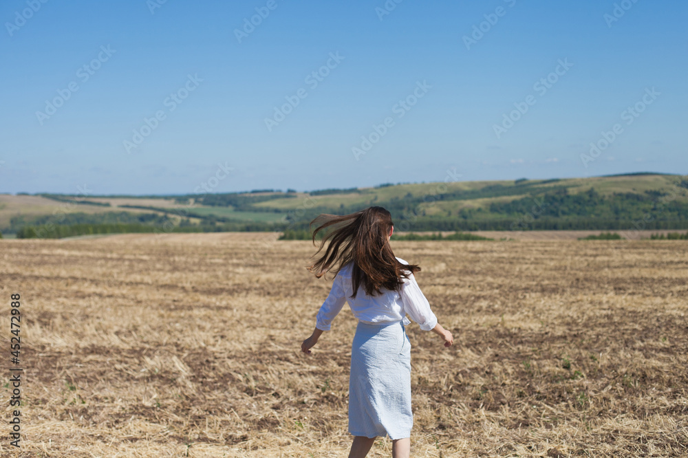 Brunette woman from behind in nature, walking in the field outdoors, dancing Brunette woman from behind in nature, walking in the field outdoors, dancing