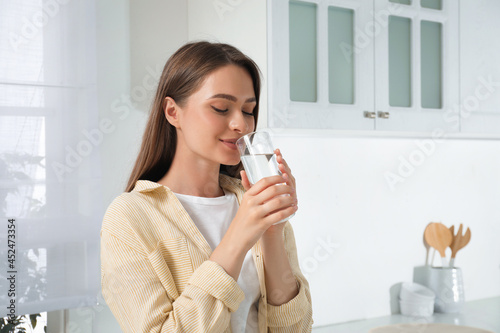 Foto Woman drinking tap water from glass in kitchen