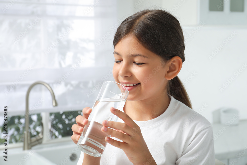 Girl drinking tap water from glass in kitchen Girl drinking tap water from glass in kitchen