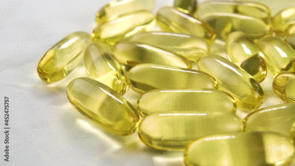 Omega 3 yellow pills with fish oil on a white surface. Macro. Dolly shot. Natural medicine concept Omega 3 yellow pills with fish oil on a white surface. Macro. Dolly shot. Natural medicine concept