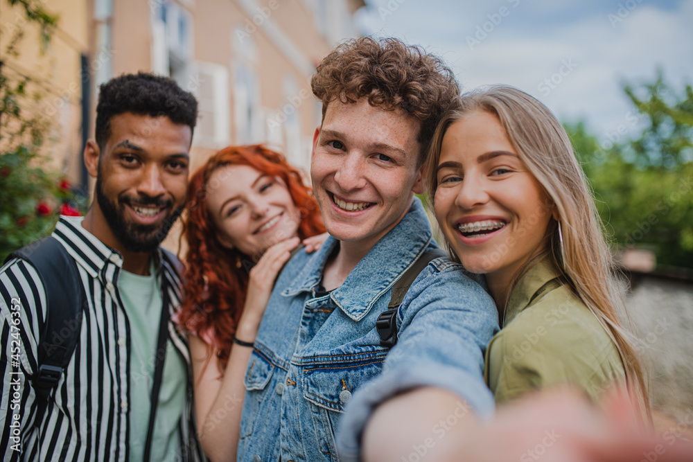 Fototapeta premium Portrait of group of young people outdoors on trip in town, taking selfie and looking at camera.