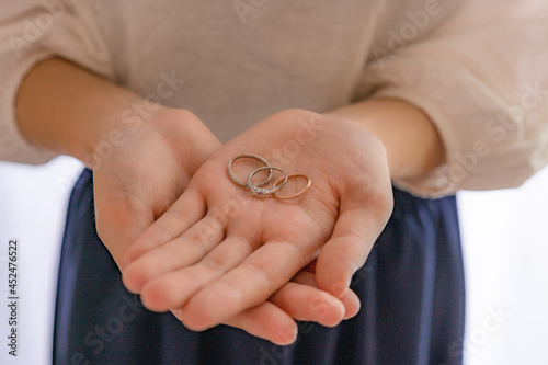 掌に乗せられた結婚指輪と婚約指輪 © らっかす