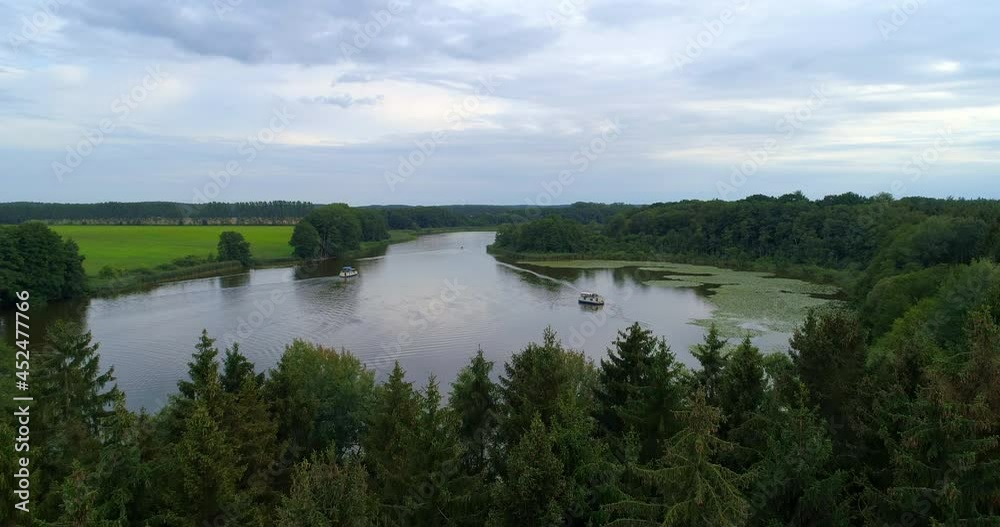 Aerial Forward Scenic View Of Boats Moving In Lake, Drone Flying Over Green Trees Against Cloudy Sky - Mecklenburg-Vorpommern, Germany Aerial Forward Scenic View Of Boats Moving In Lake, Drone Flying Over Green Trees Against Cloudy Sky - Mecklenburg-Vorpommern, Germany