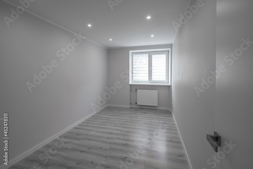 Fototapeta Naklejka Na Ścianę i Meble -  Modern interior of empty room. Apartment after renovation. White walls. Light parquet floor. Black and white.
