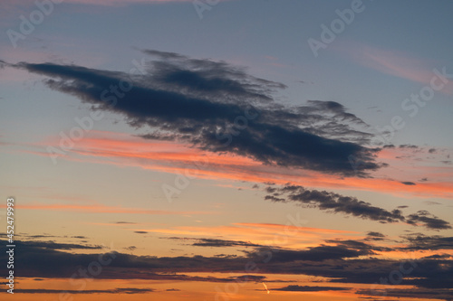 Pink, blue and gold clouds and sky at sunset on summer evening.