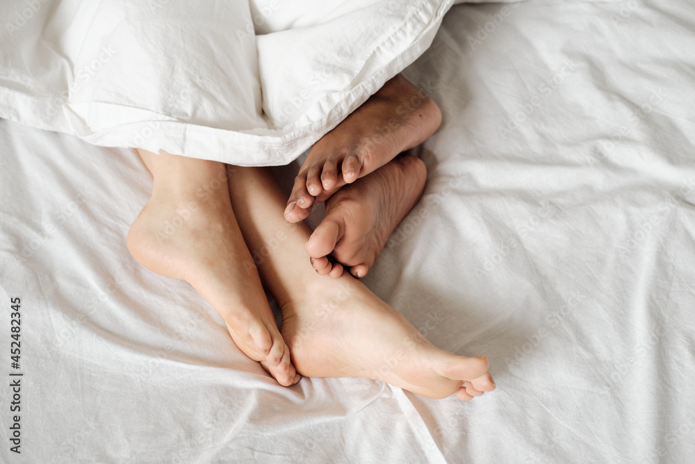 Bare feet of multiracial females sleeping together in bed Bare feet of multiracial females sleeping together in bed