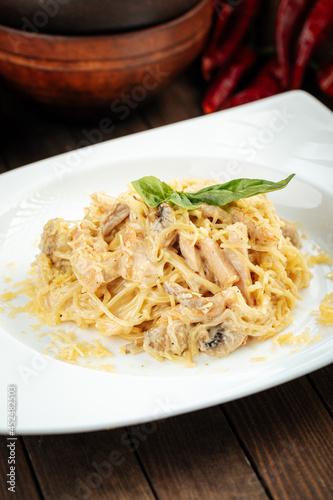 Carbonara paste with smoked chicken and mushrooms on wooden background