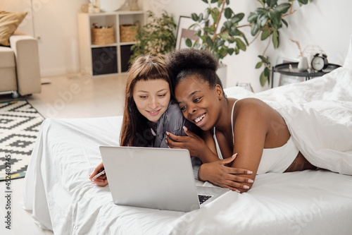 Cheerful lesbian couple looking at laptop screen during online communication