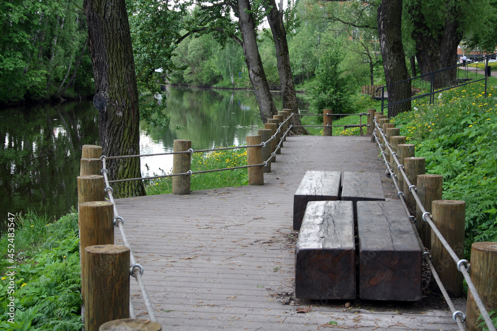 Recreation area in the park by the water. Wooden benches on the shore of the pond. Eco-friendly rest. Recreation area in the park by the water. Wooden benches on the shore of the pond. Eco-friendly rest.