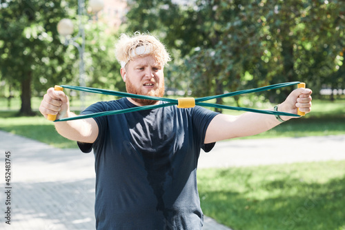 Overweight man trying to lose his weight with sports training and exercises in the park outdoors