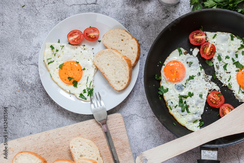 Fried eggs in a frying pan. On a concrete gray background. On the plate