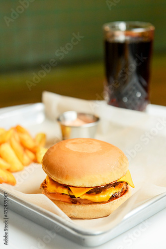 Hamburger with fries and sauce on a metal tray in restaurant, blurred background. Fast food, junk food concept.