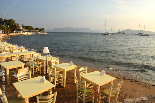 tables set for dinner on the beach at sunset over the sea in Aegina in Greece © sergioboccardo