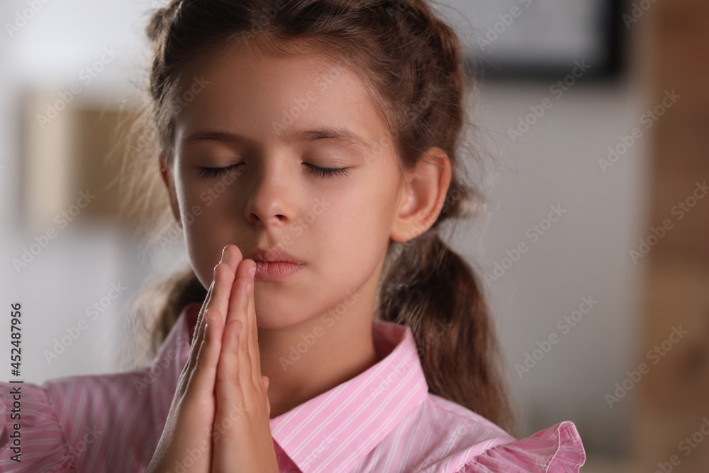 Cute little girl with hands clasped together praying at home Stock ...