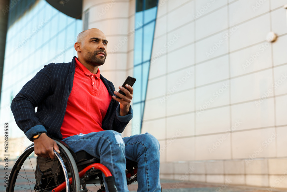 Unshaven man using mobile phone while sitting in wheelchair Unshaven man using mobile phone while sitting in wheelchair