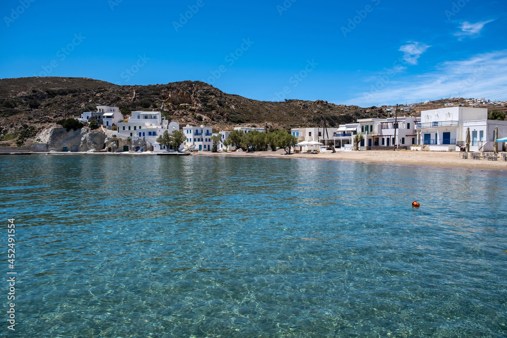 Kimolos island Psathi village Cyclades Greece. Whitewashed buildings sandy beach calm blue sea