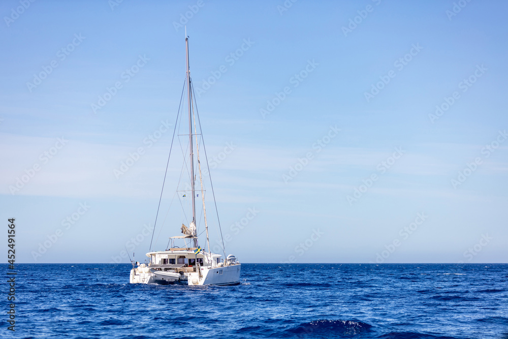 Kimolos island, Cyclades Greece. Moored yacht in blue Aegean sea clear blue sky background.