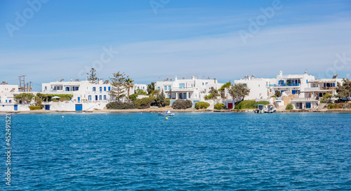 Milos island Cyclades Greece. Whitewashed buildings at seaside fishing boats moored in calm blue sea photo