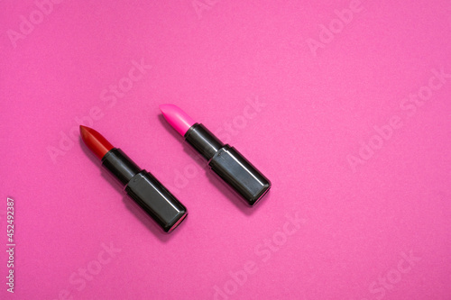 Fashion cosmetics photo of red and pink lipsticks on a pink background 